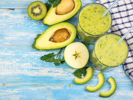 A freshly prepared smoothie of avocado, banana, orange, lemon and kiwi on a wooden table. Diet vegetarian food. Raw foods. Top view.の写真素材