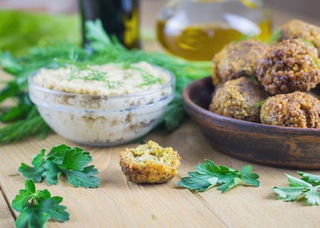 Freshly cooked falafel on clay bowl on a wooden table with tahini sauce. Eastern vegetarian meal of chickpea.の写真素材