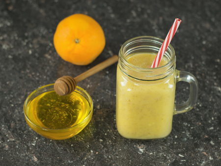 Freshly made smoothies with mango, banana, orange and cereal on a dark stone table.の写真素材