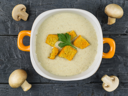 Bowl of cream soup of champignons with croutons on wooden rustic table. Cream soup of mushrooms, potatoes and cream with spices. The view from the top.の写真素材