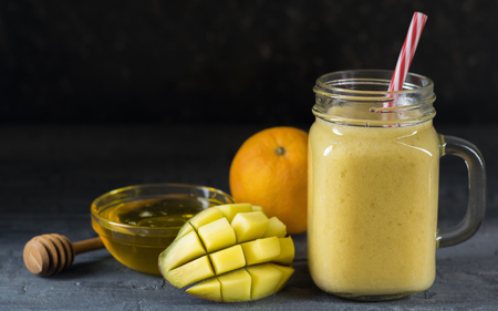 A smoothie of mango, banana, honey and cereal on a black background.の写真素材