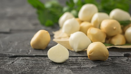 Freshly prepared smoked and regular mozzarella cheese in paper on a wooden table. Rustic food from natural products.の写真素材