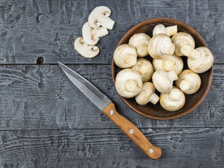 Fresh mushrooms in clay bowl on a rustic wooden table. Vegetarian food is on the table. Healthy eating.の写真素材