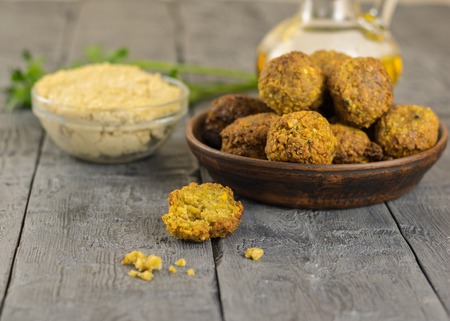 Freshly cooked falafel on clay bowl on a wooden table with tahini sauce. Eastern vegetarian meal of chickpea.の写真素材