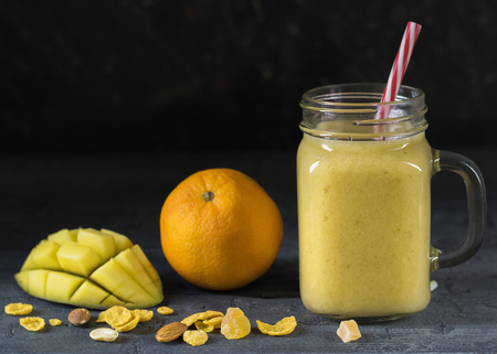 A smoothie of mango, banana, honey and cereal on a black background. Diet healthy eating of natural foods.の写真素材
