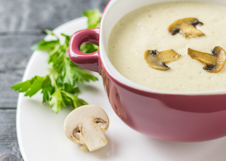 Freshly prepared cream soup of mushrooms with croutons on a white plate. Cream soup of mushrooms, potatoes and cream with spices. The decoration of raw mushrooms.の写真素材