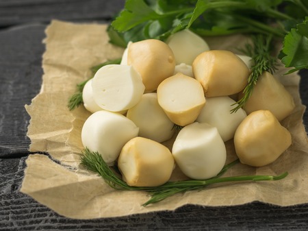 Freshly prepared smoked and regular mozzarella cheese in paper on a wooden table. Rustic food from natural products.の写真素材
