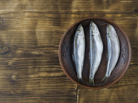 Salted herring in a clay bowl on wooden rustic table. The view from the top. Natural food from the ocean.の写真素材