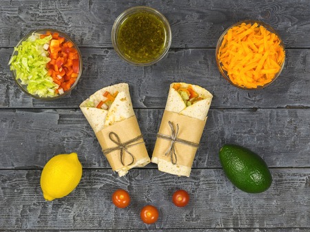 Cabbage, carrot, pepper, avocado, tomatoes in pita bread on a rustic table. Vegetarian food. The view from the top.の写真素材