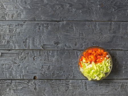 Cabbage and bell pepper in a glass bowl on a dark rustic table. The view from the top. Vegetarian food.の写真素材