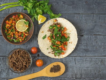 Cake made of cornmeal with ground beef and vegetables Mexican tacos on a wooden table. Ingredients...