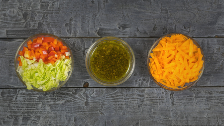 Cabbage, carrot, oil, herbs and bell pepper in a glass bowl on a dark rustic table. The view from the top. Vegetarian food.の写真素材