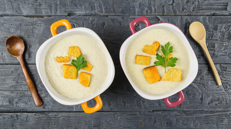 Two bowls of cream soup of champignons with croutons on wooden rustic table. Cream soup of mushrooms, potatoes and cream with spices. The view from the top.の写真素材