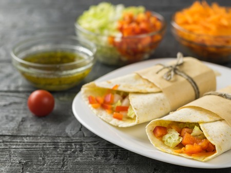Cabbage, carrot, pepper, avocado, tomatoes in pita bread on a rustic table. Vegetarian food. The view from the top.の写真素材