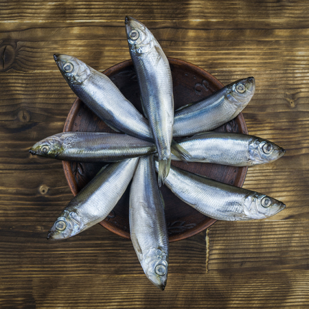 Salted herring in a clay bowl on wooden rustic table. The view from the top. Natural food from the ocean.の写真素材