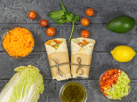 Cabbage, carrot, pepper, avocado, tomatoes in pita bread on a rustic table. Vegetarian food. The view from the top.の写真素材