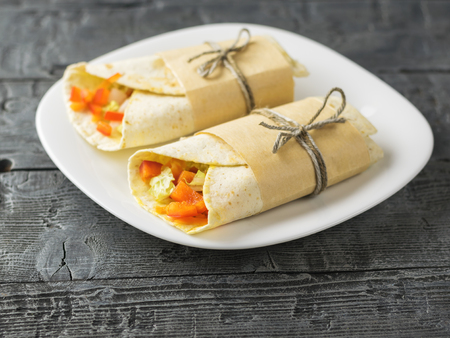Cabbage, carrot, pepper, avocado, tomatoes in pita bread on a rustic table. Vegetarian foodの写真素材
