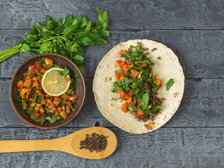 Cake made of cornmeal with ground beef and vegetables Mexican tacos on a wooden table. Ingredients for making Mexican tacos. The view from the top.の写真素材