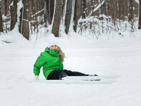 Little girl in a bright green suit learns to ski in the woods.の写真素材