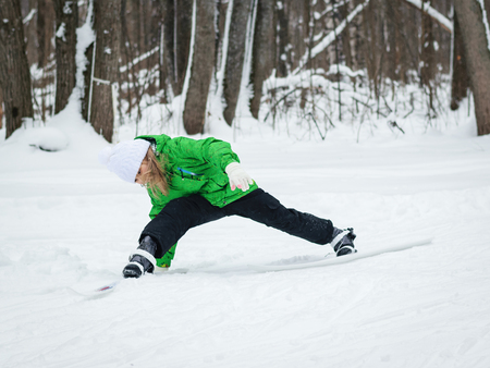 Little girl in a bright green suit learns to ski in the woods. The concept of sports education of children.の写真素材
