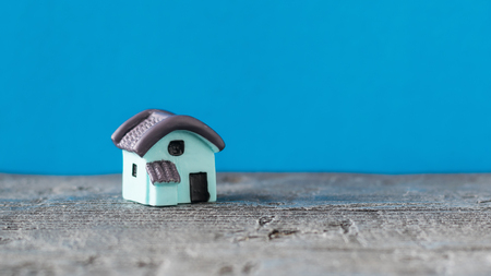 Model house on wooden table in sunlight on a blue background. The concept of building a new home. Selective focus.の写真素材