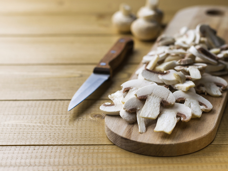 Fresh sliced mushrooms on chopping Board on wooden table. Products for vegetarian diet.の写真素材