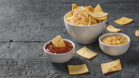 Mexican tortilla chips in a bowl with sauce and mustard on the table. A dish of Mexican cuisine.の写真素材