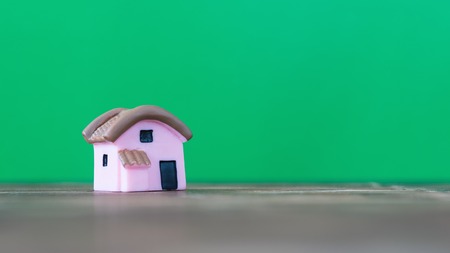 Model house on wooden table in sunlight on a green background. The concept of building a new home.の写真素材