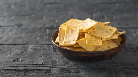 Mexican tortilla chips with cheese in a clay bowl on a rustic wooden table. Copy space.の写真素材