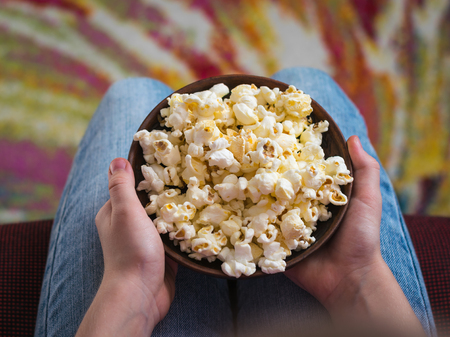 Baby in a chair on a colorful background with a bowl of popcorn.の写真素材