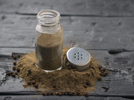An open jar of ground pepper on a rustic table.の写真素材