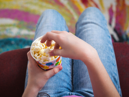 Baby in a chair on a colorful background with a bowl of popcorn. The concept of partying and watching of movies.の写真素材