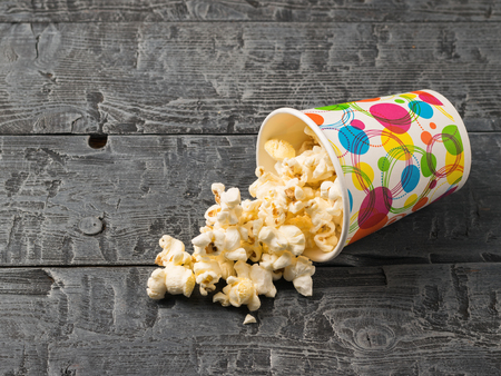 Inverted colorful glass of popcorn on a black rustic table.の写真素材