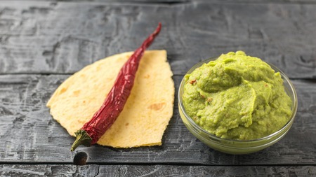 Chilli pepper on pieces of pita and fresh guacamole in bowl on the table. Diet vegetarian Mexican food avocado. Raw food.の写真素材