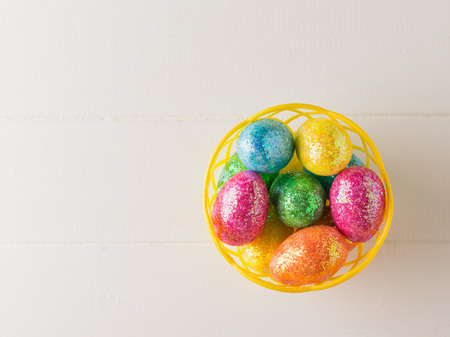 Basket with colorful eggs on a white rustic table. The view from the top.の写真素材