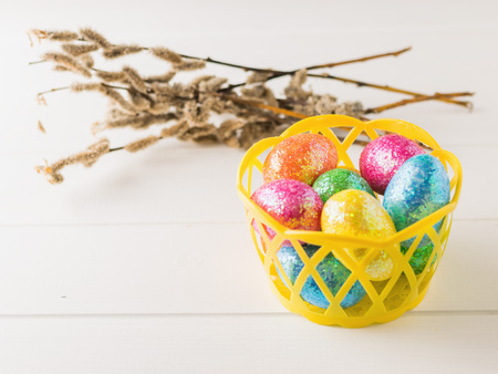 Basket with colorful eggs on a white rustic table.の写真素材