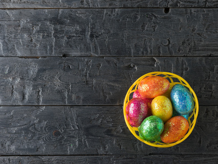 Basket with colorful eggs on a black rustic table. Decorations for the Easter table. The view from the top.の写真素材