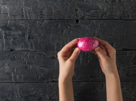 Easter pink egg in the hands of a child. Decorations for the Easter table.の写真素材