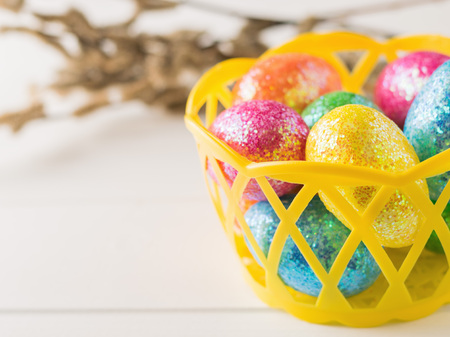 Basket with colorful eggs on a white rustic table. Decorations for the Easter table.の写真素材