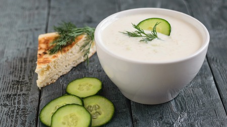 Freshly made tzatziki in a white bowl on a dark wooden table. Vegetarian Greek cuisine.の写真素材