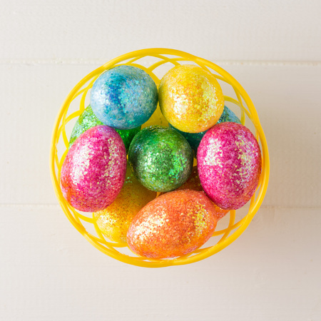 Basket with colorful eggs on a white rustic table. Decorations for the Easter table. The view from the top.の写真素材