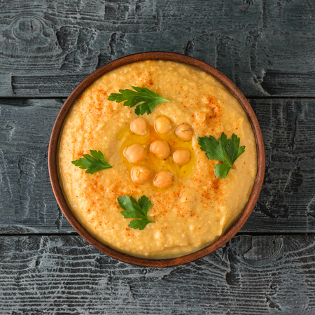 Bowl with fresh hummus on a wooden table. Vegetarian middle Eastern dish and chickpea.の写真素材