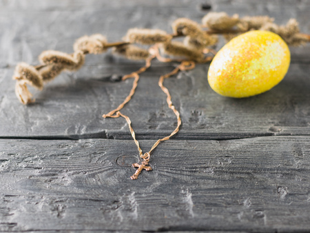 Gold jewelry, a Golden egg and a sprig of willow on a rustic table. The decoration of the Easter table. Great Christian holiday.の写真素材