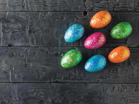A lot of colorful eggs scattered on a dark rustic table. The decoration of the Easter table. Great Christian holiday. The view from the top.の写真素材