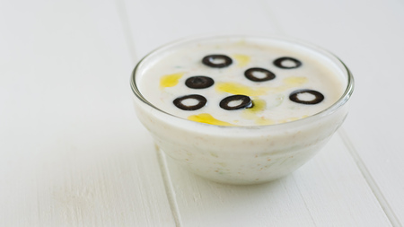 Tzatziki sauce bowl decorated with olives on a white wooden table. Vegetarian Greek cuisine.の写真素材