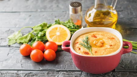Bowl with hummus, olive oil, tomatoes, herbs and lemon on the rustic table. Vegetarian middle Eastern dish and chickpea.の写真素材
