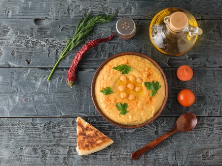 Fresh hummus, wooden spoon, a piece of lavash, tomatoes on a wooden table. Vegetarian middle Eastern dish and chickpea. The view from the top.の写真素材