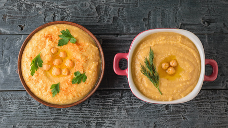Two bowls with fresh hummus on a wooden table. Vegetarian middle Eastern dish and chickpea. The view from the top.の写真素材