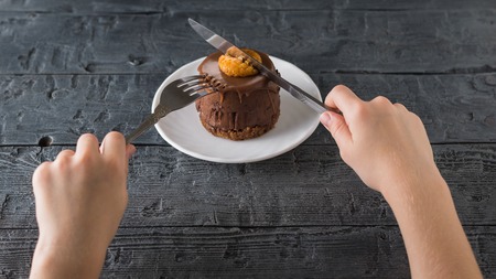 The child cuts a fresh dessert with a knife in a white Cup on a wooden table. Delicious dessert on the rustic table.の写真素材