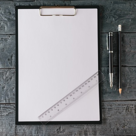 Notebook with pen, pencil and ruler on dark wooden table. The view from the top. Concept of...